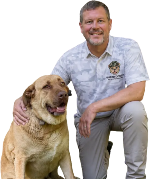 Guard Doody owner Christopher Glass kneeling beside his tan dog, wearing a Guard Doody camo polo